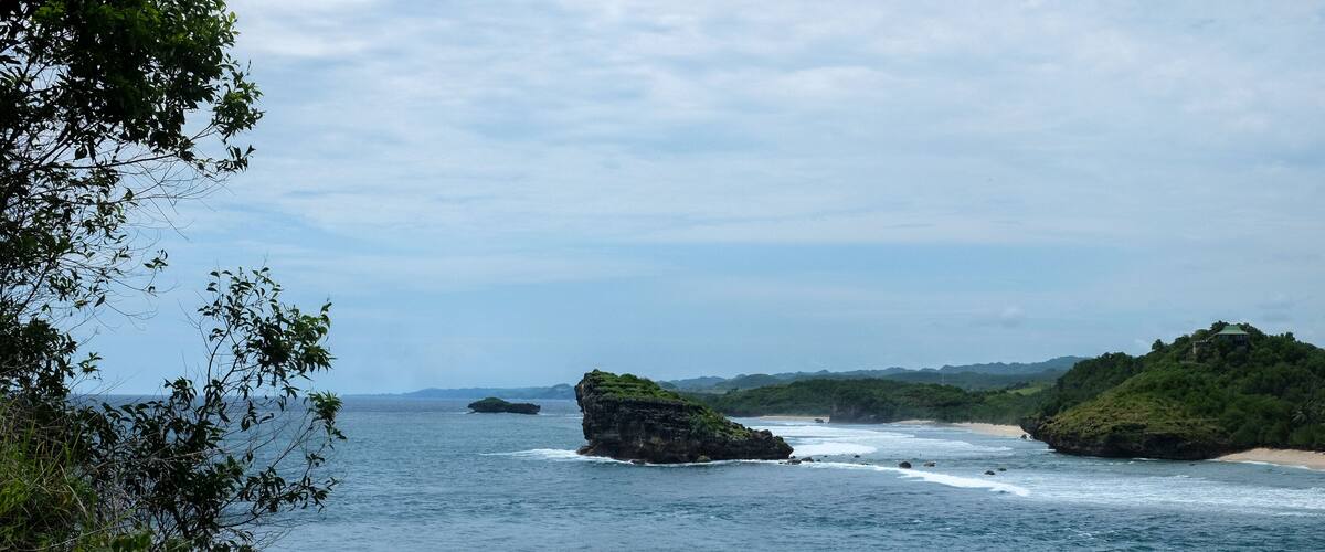 A coastal landscape with rocky outcrops and a beach.