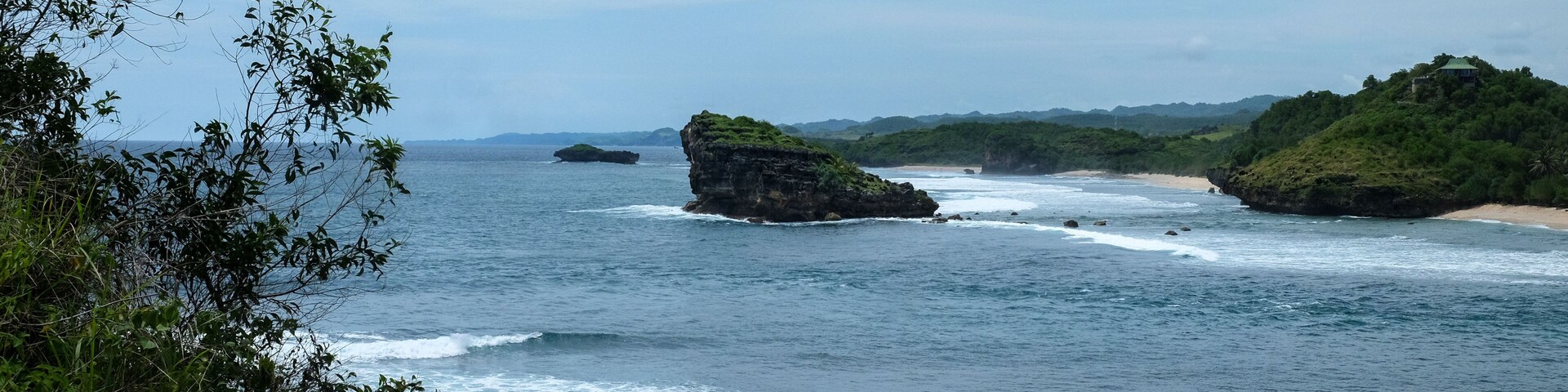 A coastal landscape with rocky outcrops and a beach.