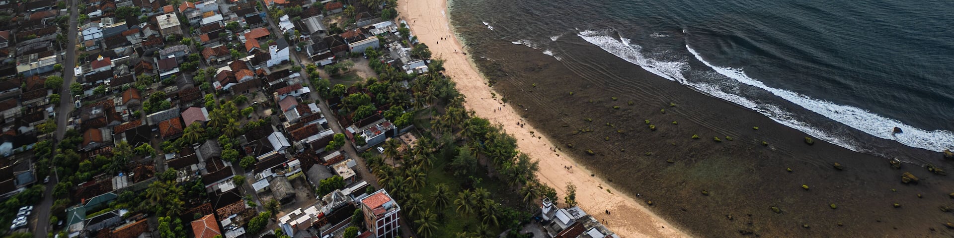 Aerial view of Watu Karung Beach, Pacitan, East Java, Indonesia with crashing waves during the day. Cape with cliffs by the sea and green plants around at tropical island