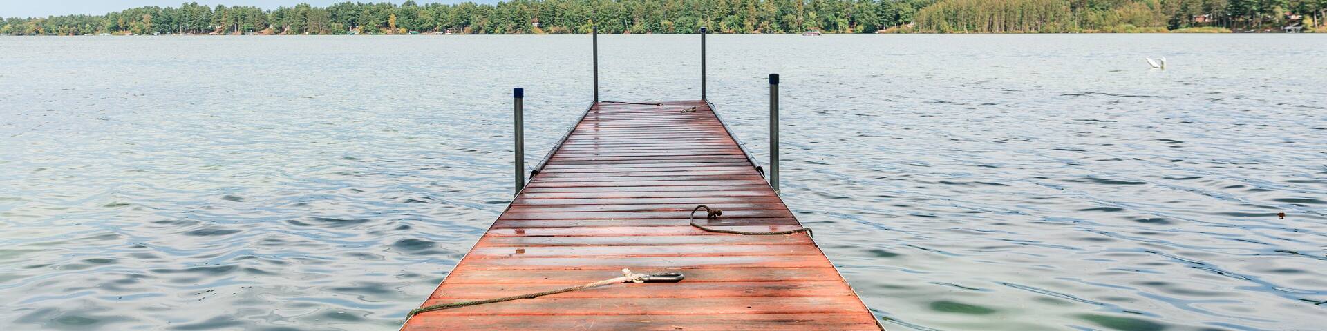 Wooden dock extending into lake under blue sky