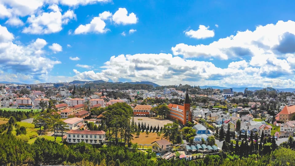 A cityscape with a prominent church steeple, a large open square, and a mountainous backdrop.