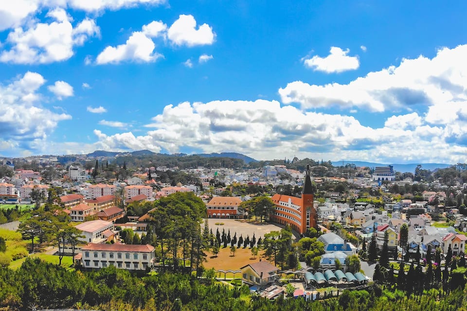 A cityscape with a prominent church steeple, a large open square, and a mountainous backdrop.