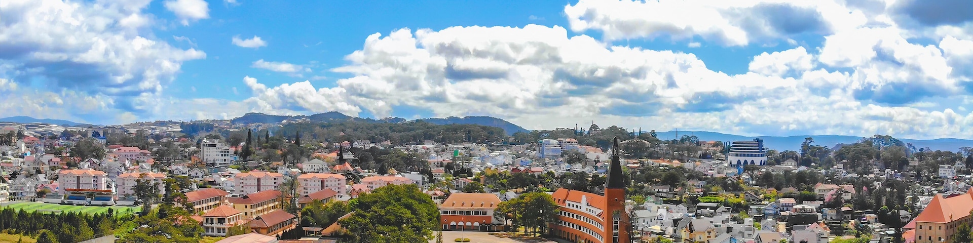 A cityscape with a prominent church steeple, a large open square, and a mountainous backdrop.