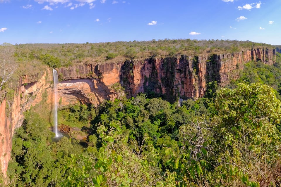 Ein Canyons mit Wasserfall, dichtem Grünwald und steilen Felswänden.