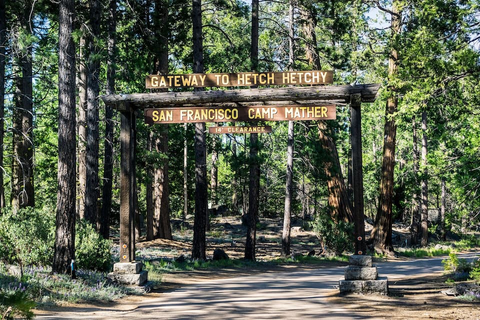 Um sinal de madeira em um camping arborizado com a inscrição 'Gateway to Hetch Hetchy' e 'San Francisco Camp Matpher'.