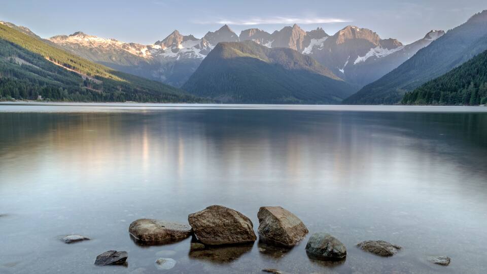 A calm lake with a mountain range in the background.