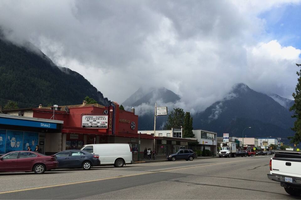 Une ville avec un cinéma, un fourgon blanc et une montagne en arrière-plan.