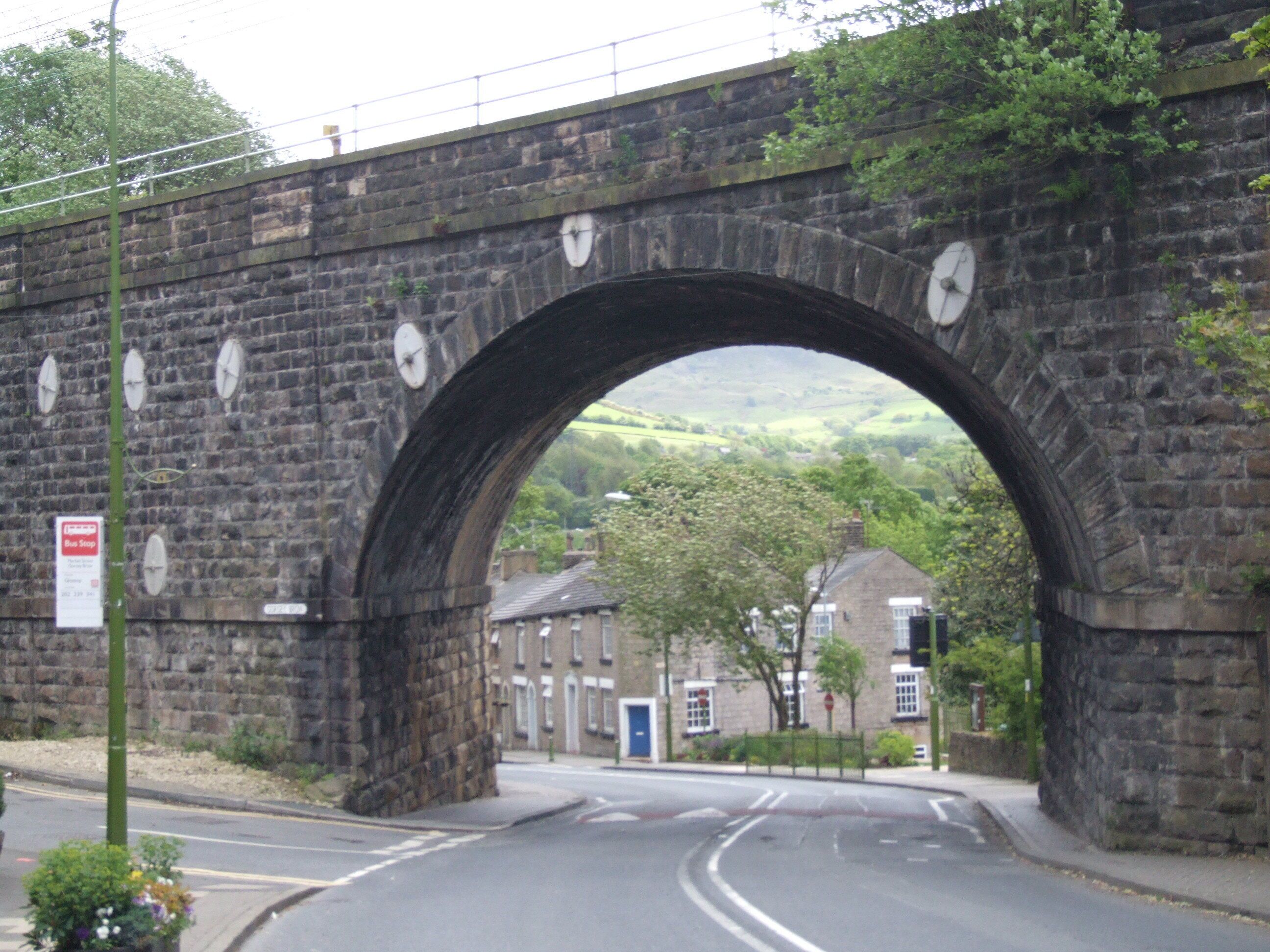 Broadbottom is a village, near Hyde, Greater Manchester in the valley of the River Etherow. From Mottram Road, Market Street by Gorsey Brow, looking under the south through railway arch towards Charlesworth. Camera location 53° 26′ 27.24″ N, 2° 00′ 37.8″ W View this and other nearby images on: OpenStreetMap - Google Earth 53.440900; -2.010500