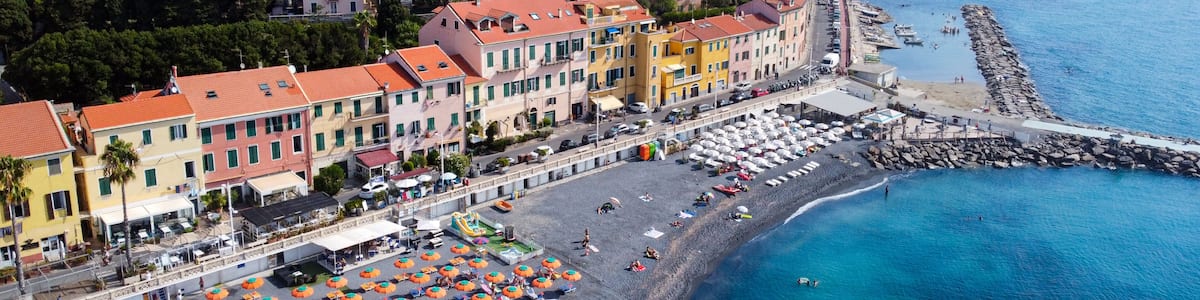 A coastal town with colorful buildings, a sandy beach, and a rocky breakwater.