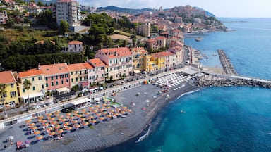A coastal town with colorful buildings, a sandy beach, and a rocky breakwater.