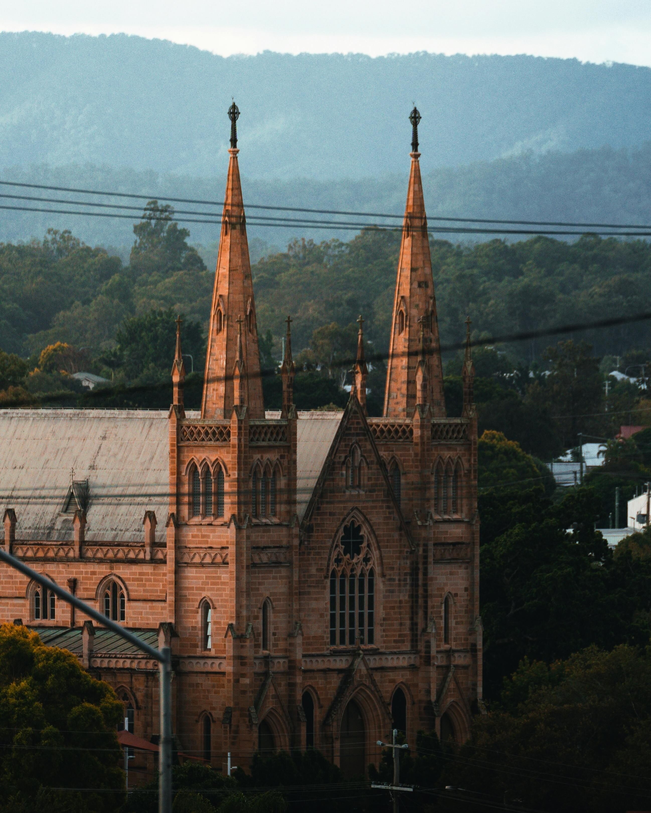 A historic brick St. Mary’s Catholic Church in Ipswich, Australia, featuring classic Gothic-style architecture, tall spires, and arched windows under a clear sky.