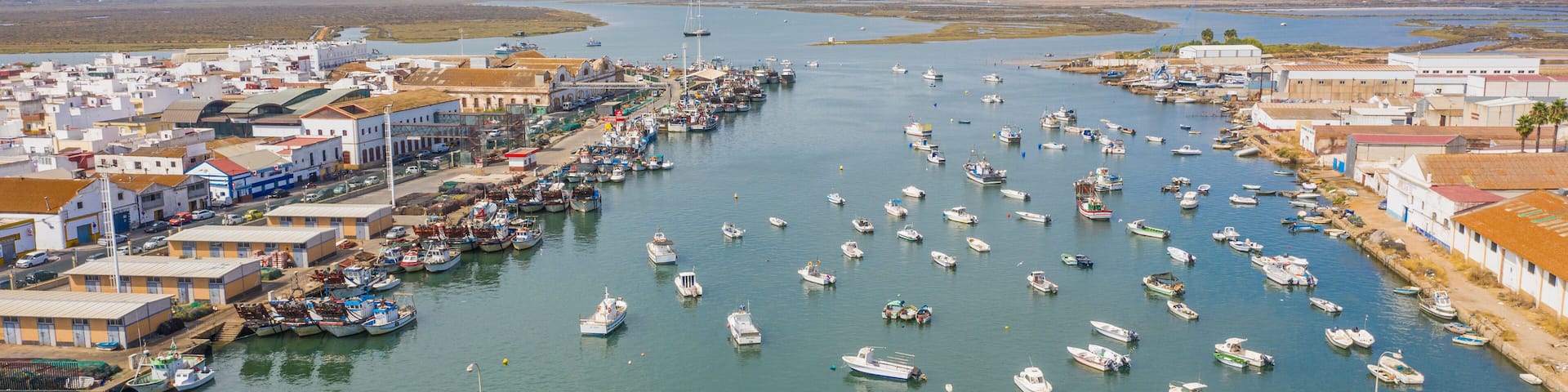 Aerial view of a harbor with the boats docked and a bridge over the Rio Carrera connecting the island of Isla Cristina, Huelva, Spain.