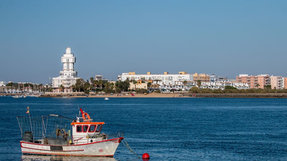 A coastal town with a lighthouse, a fishing boat, and a beach.