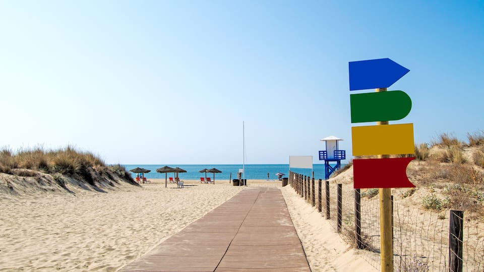 A wooden boardwalk leading to a beach with umbrellas and lounge chairs.