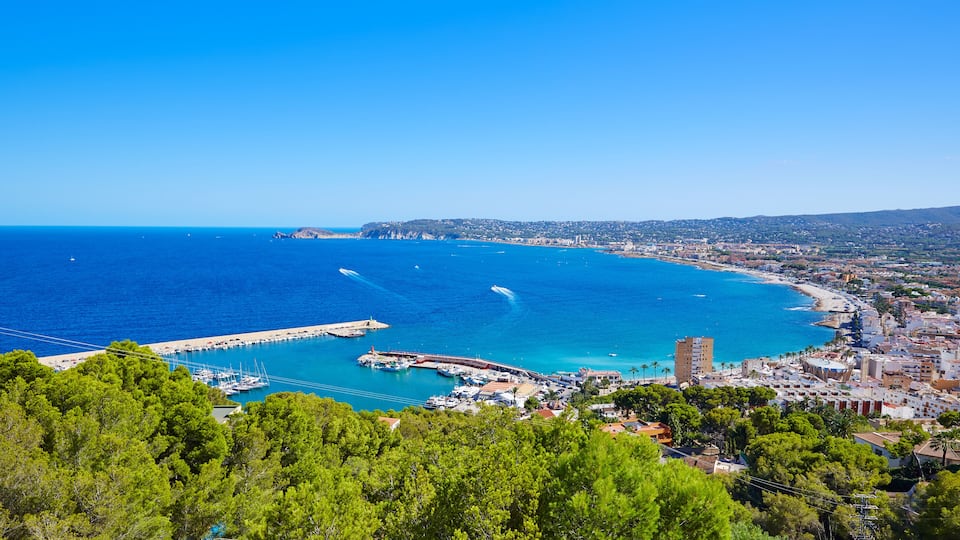 A coastal city with a marina, boats, and a clear blue sea.