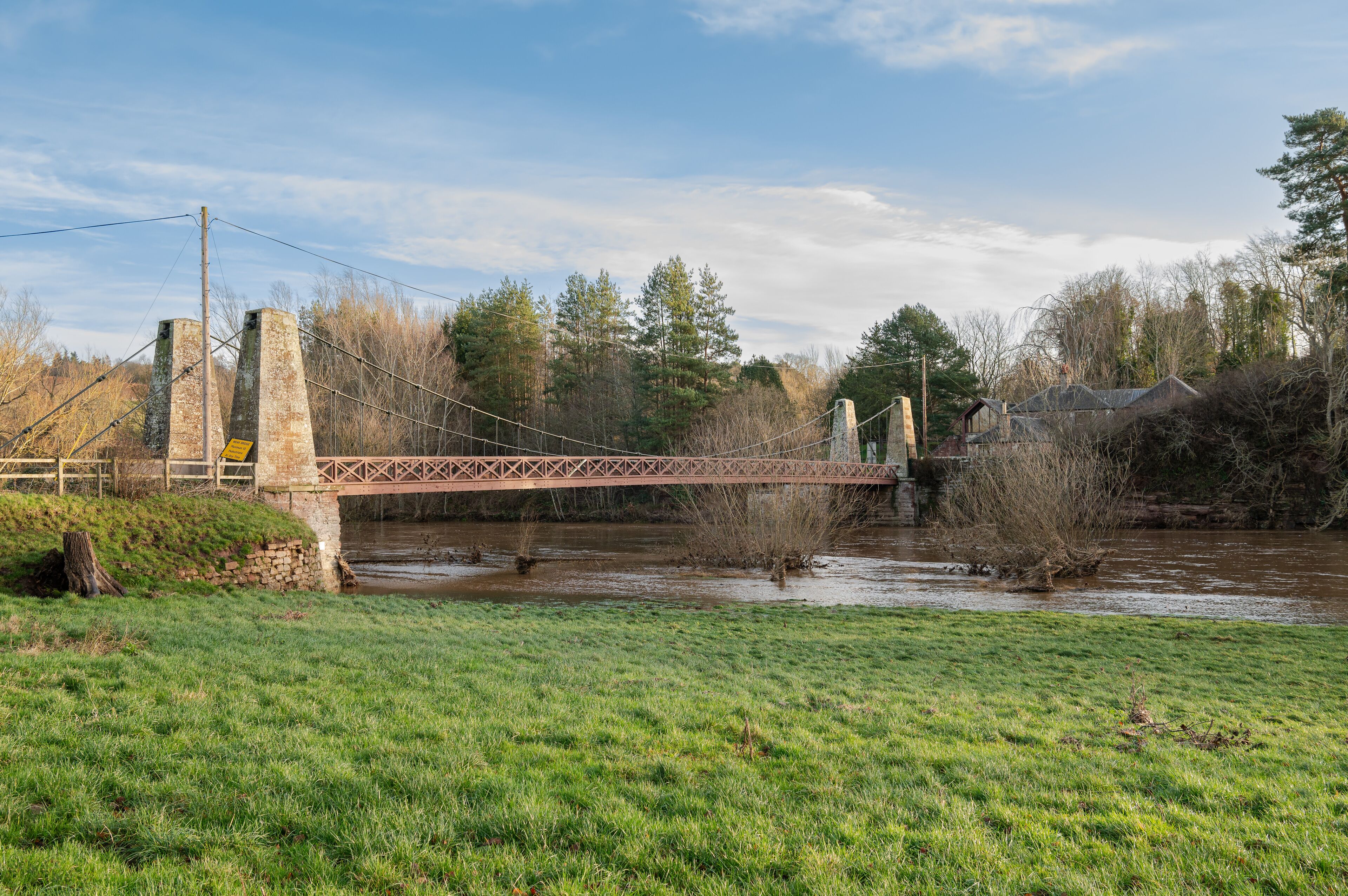 Kalemouth Suspension Bridge over the Teviot River in flood after storm Gerrit in December 2023, Scottish Borders, UK