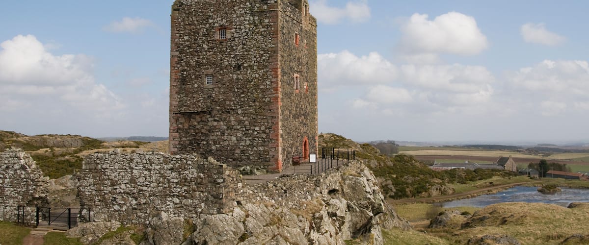 A stone tower with a pointed roof, surrounded by rocky terrain and a river.