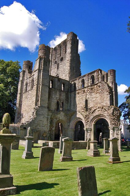 A historic castle with ruins, surrounded by a cemetery with headstones.