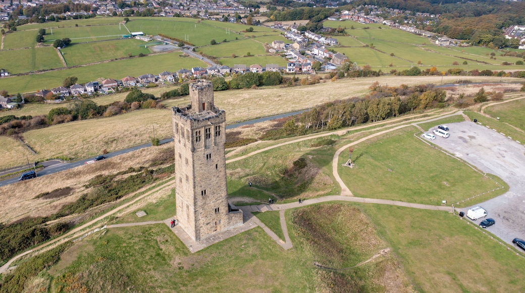 A historic tower surrounded by green fields and a small parking area.