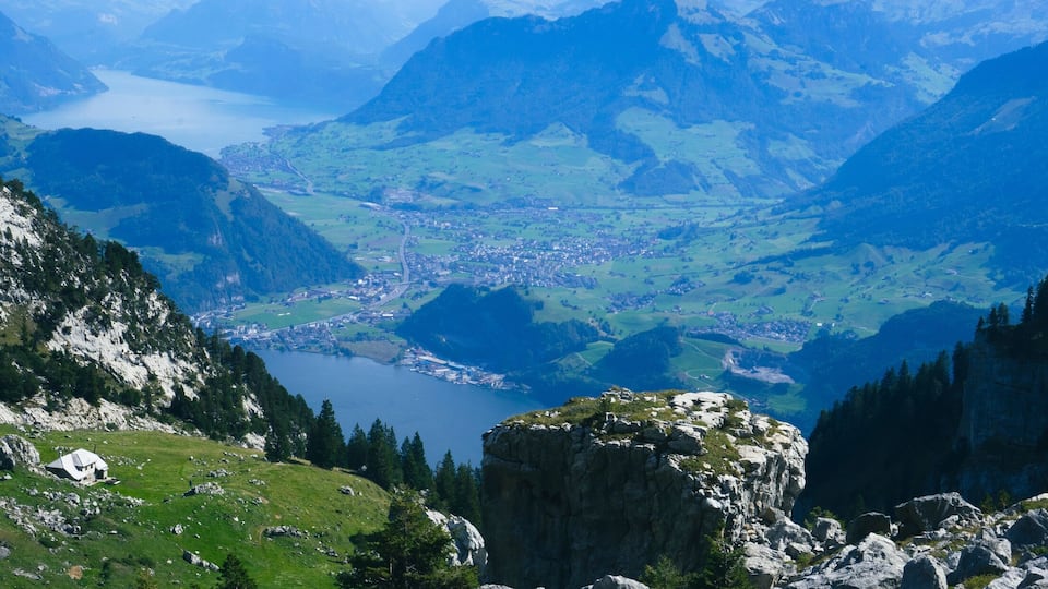 A mountainous landscape with a valley, a lake, and a small settlement.