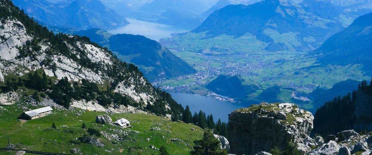 A mountainous landscape with a valley, a lake, and a small settlement.