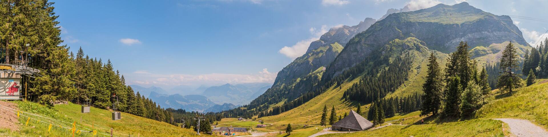 A mountainous landscape with a ski lift, a small building, and a winding road.