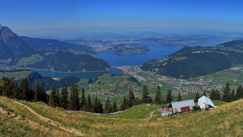 A mountainous landscape with a lake, a town, and a white-roofed building.