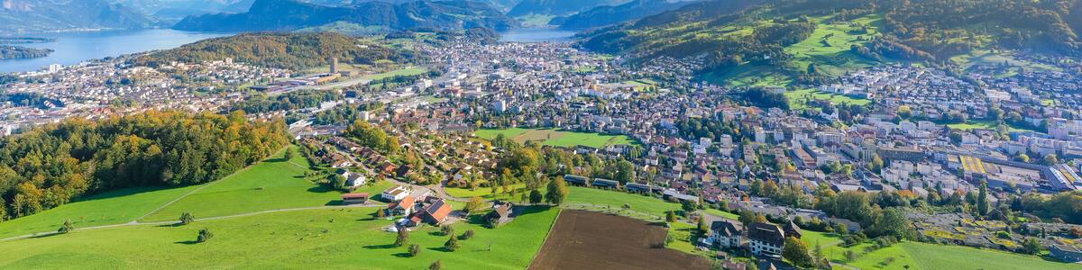 Une vue panoramique d’une ville nichée dans une vallée, avec un lac et des montagnes en arrière-plan.