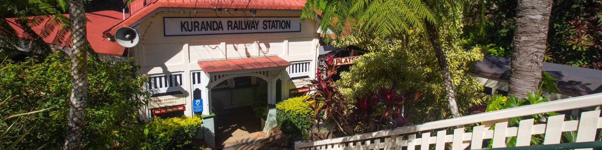 A station building with a red roof and the sign "KURANDA RAILWAY STATION".