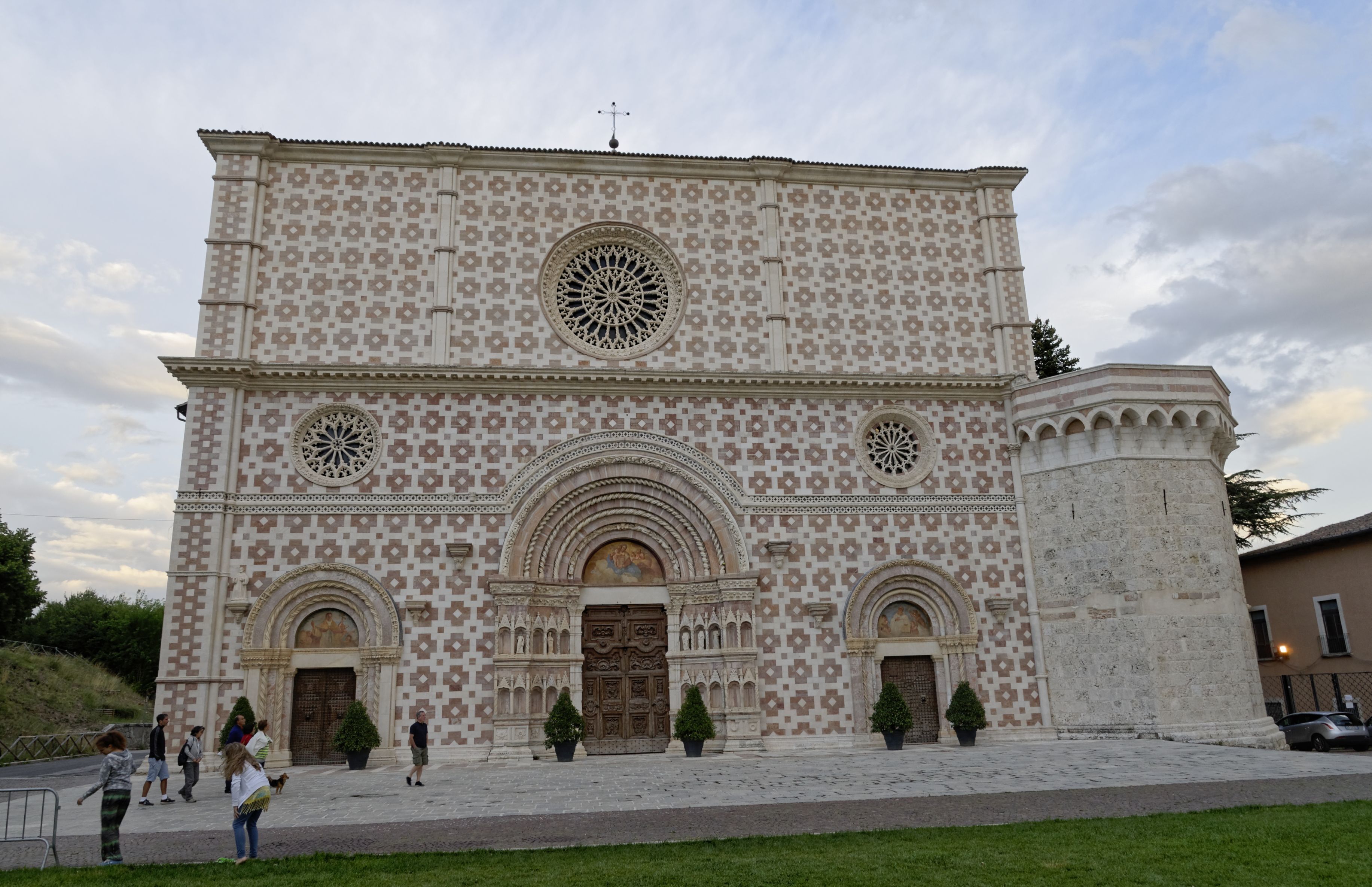 A historic building with intricate geometric tile patterns, large arched doorways, and a prominent circular window.