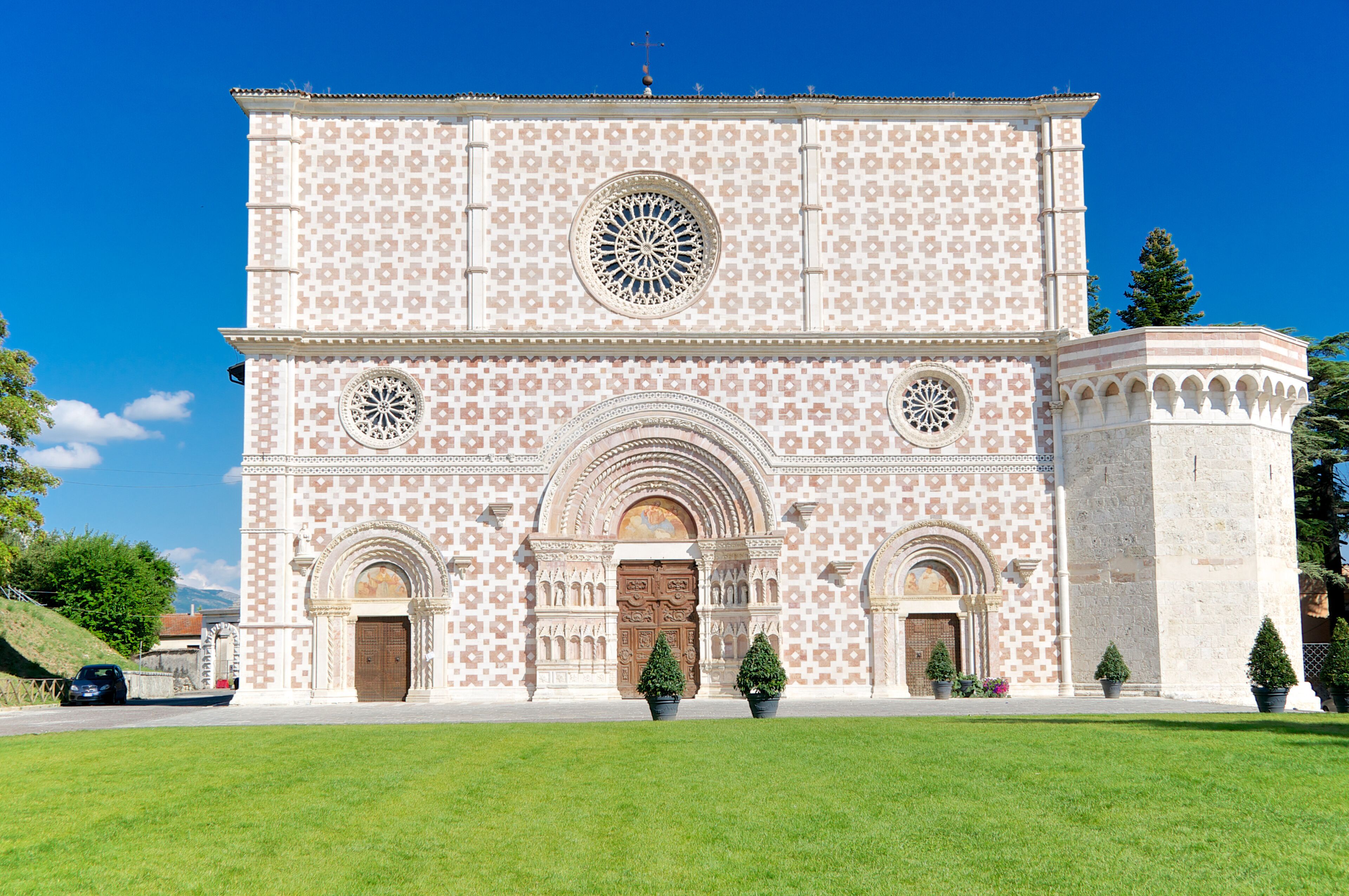 A large building with a patterned facade, arched doorways, and a central circular window.