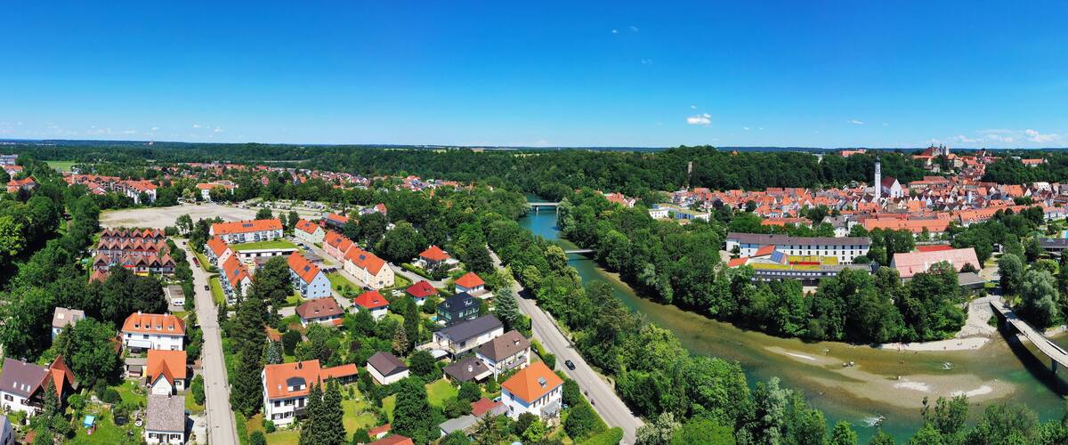 A river flowing through a town with red-roofed houses and a bridge.