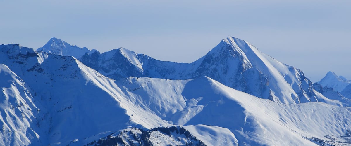 A snow-covered mountain range with sharp peaks and deep valleys.