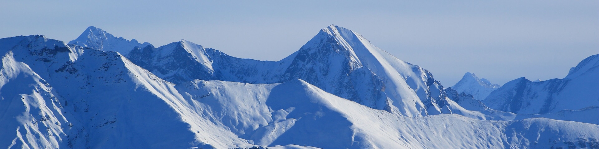A snow-covered mountain range with sharp peaks and deep valleys.