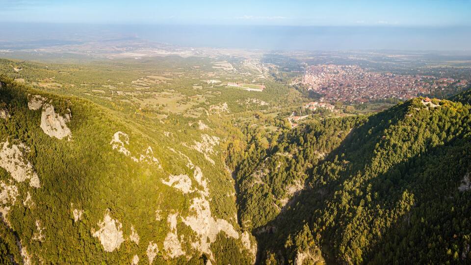 Aerial drone panoramic view of deep gorge and rocky ridge near Mountain Olympus and Litochoro village in the distance