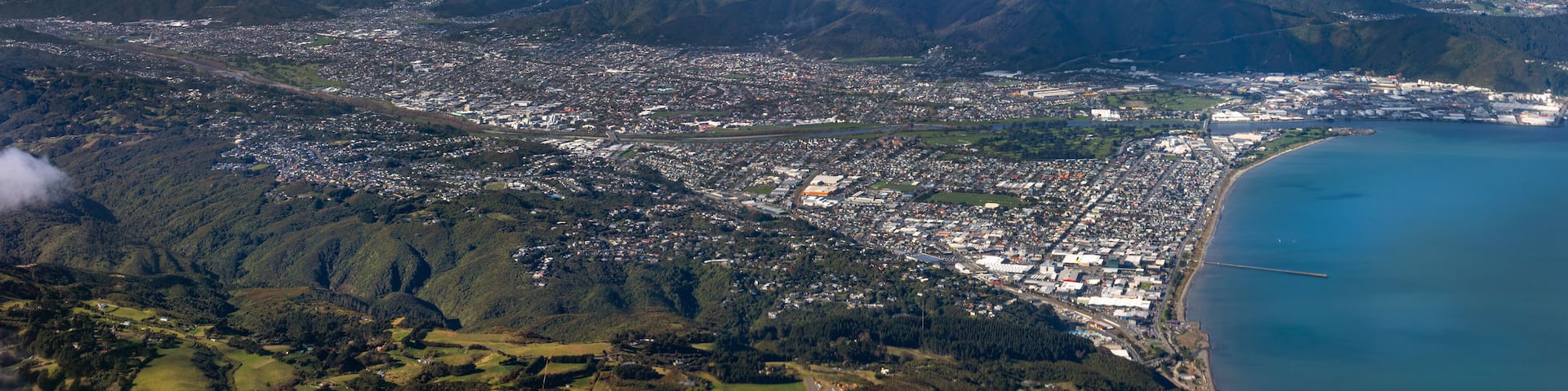 Lower Hutt, Wellington, New Zealand. Panoramic aerial view. Hutt River flows out to sea above Petone Beach at far right. Wainuiomata over the hill at top right.