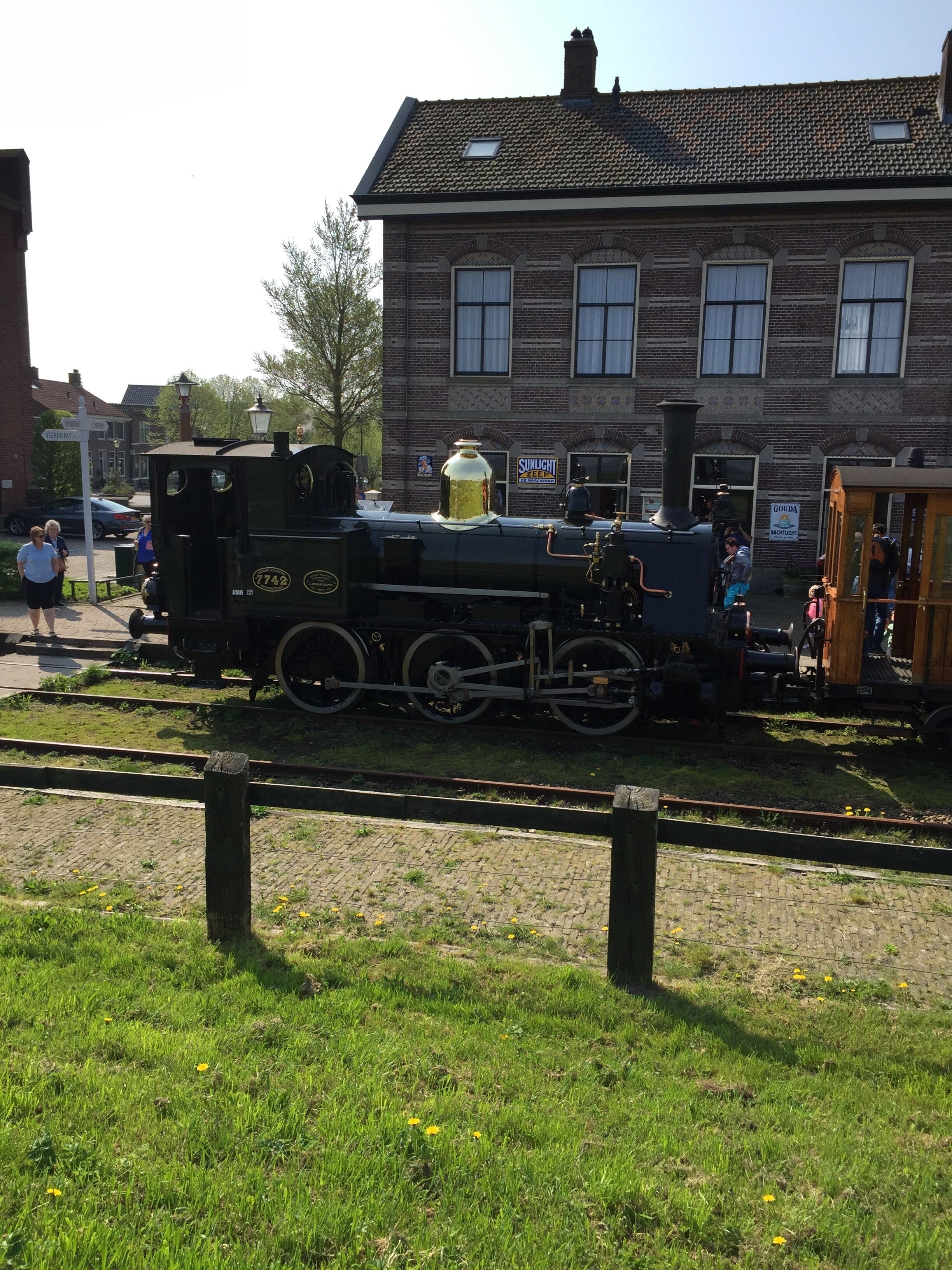 A steam locomotive with the number 7742 parked next to a brick building.