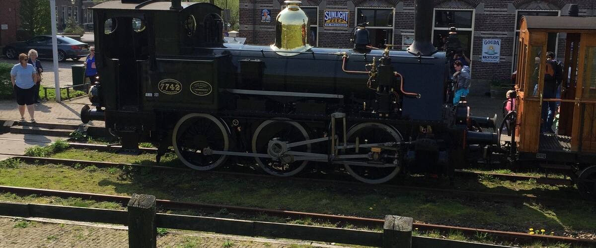 A steam locomotive with the number 7742 parked next to a brick building.