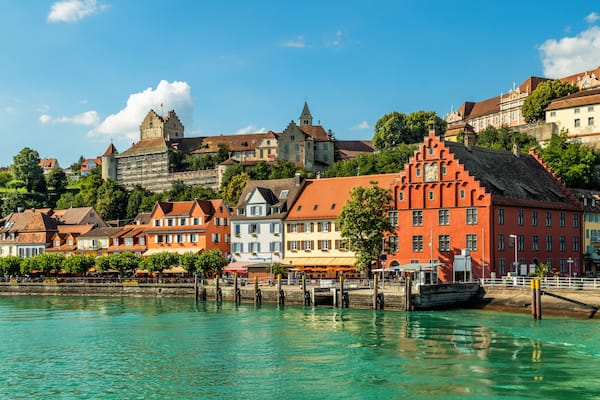 Ein Ufer mit bunten Gebäuden, einer Burg und einem Boot, das an der Pier festgemacht ist.