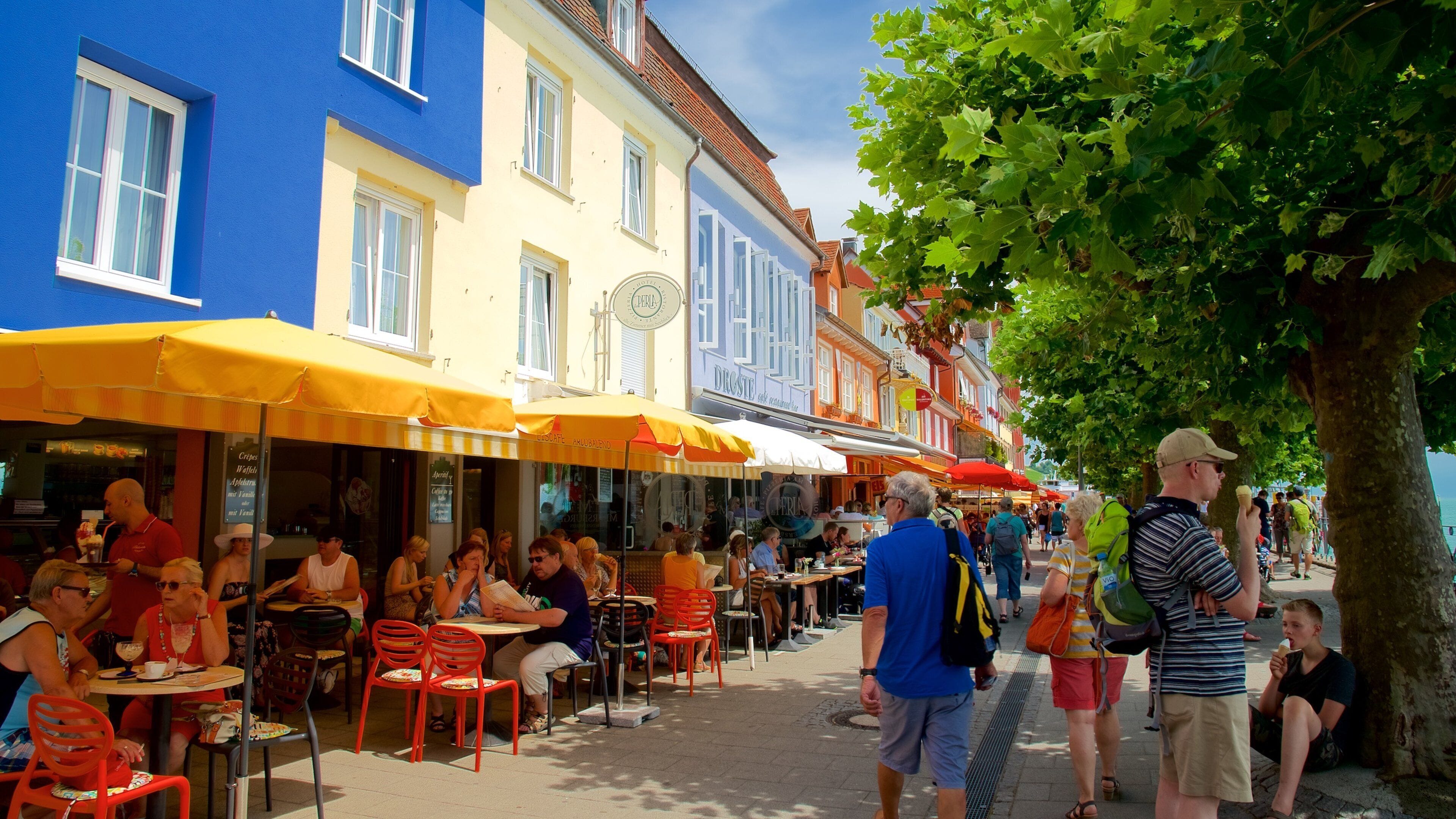 Una calle animada con cafés al aire libre, gente cenando y edificios coloridos.
