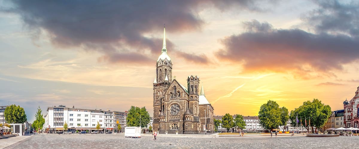 Eine historische Kirche mit einem hohen Kirchturm, einem Glockenturm und einem modernen Gebäude mit einer farbenfrohen Fassade.