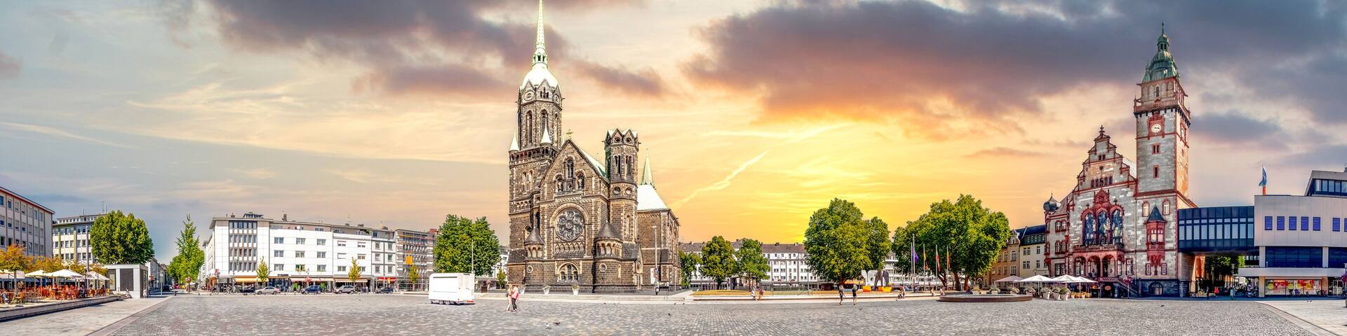 A historic church with a tall spire, a clock tower, and a modern building with a colorful facade.