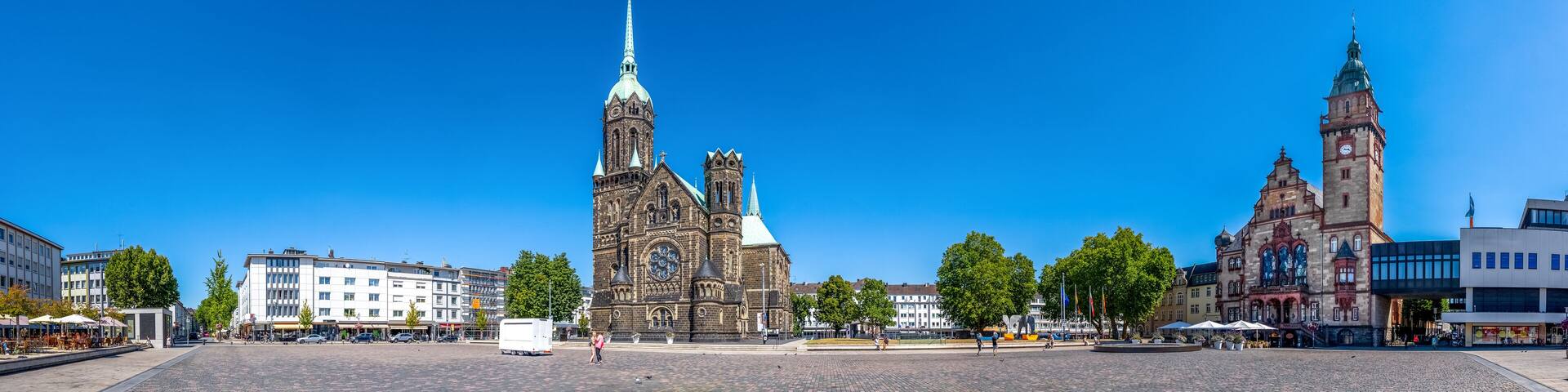 A historic church with a tall spire, a clock tower, and a modern building with a glass facade.
