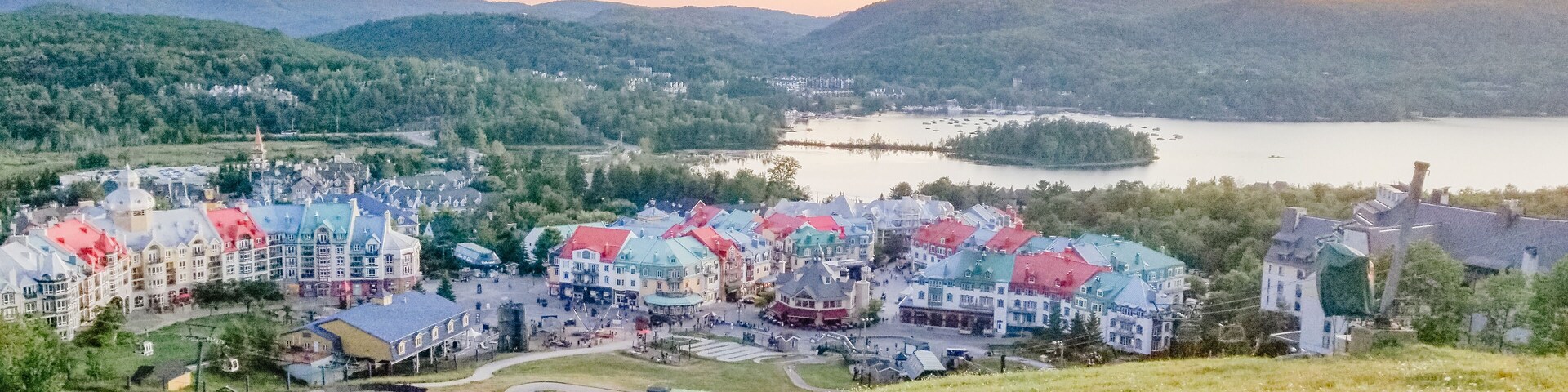 Un pueblo con edificios coloridos junto a un lago, rodeado de colinas.