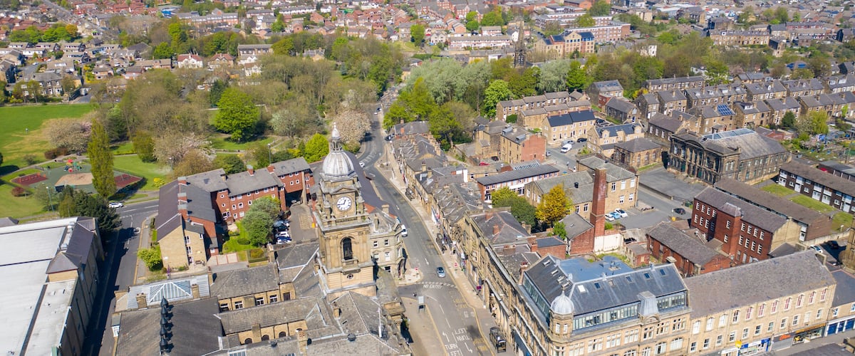 An aerial view of a historic town with prominent buildings, a central clock tower, and a mix of residential and commercial structures.