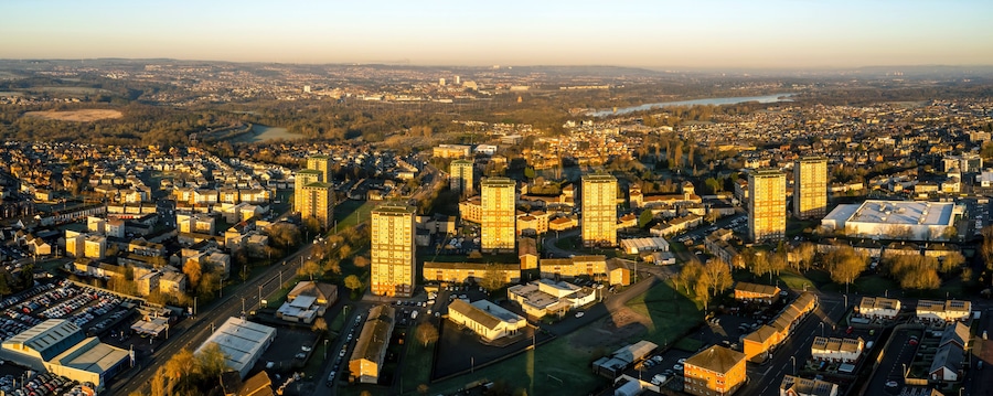 An aerial view of a cityscape with dense urban development, a river, and surrounding greenery.