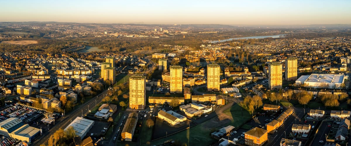 An aerial view of a cityscape with dense urban development, a river, and surrounding greenery.