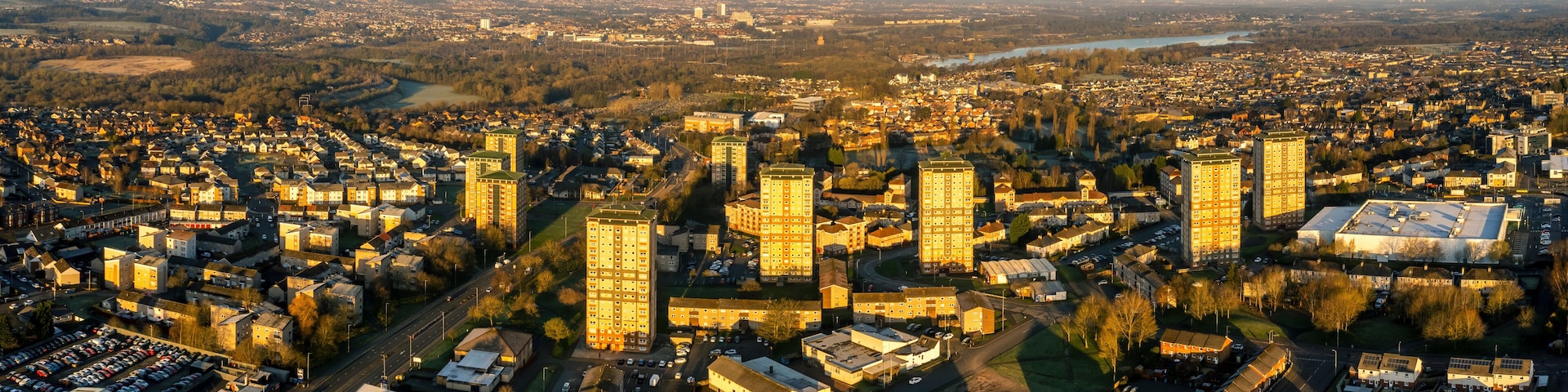 An aerial view of a cityscape with dense urban development, a river, and surrounding greenery.