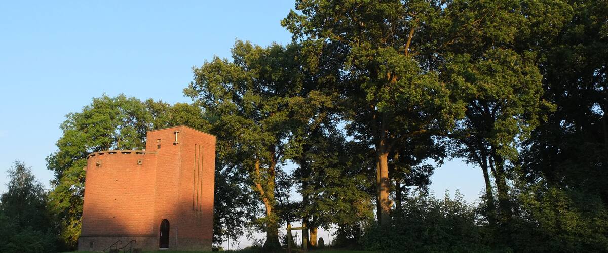 A brick tower surrounded by lush green trees and grass.