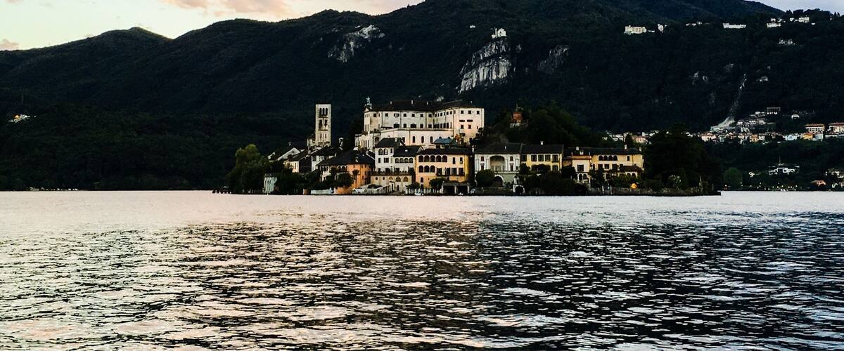 A coastal town with a prominent church and buildings on a hillside, overlooking a body of water.